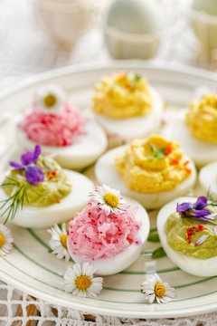 Deviled eggs with various fillings decorated with fresh herbs and edible flowers