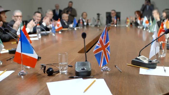 United Kingdom delegation at international negotiations. First-person view. Large group of politicians applaud the speaker and raise hands to vote.