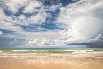 Tropical beach scenery at Andaman sea in Phuket - seconds before storm, Thailand. Exotic sea view of tropical summer paradise beach at Phuket island with sunny sky and heavy rainy clouds on horizon