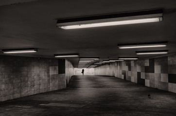 Obraz premium Black and white image of an underground passage. In the background, the silhouette of a woman is visible.