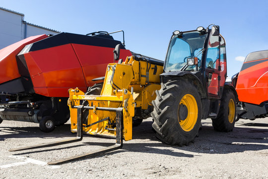 Large yellow agricultural telescopic loader in the parking lot.