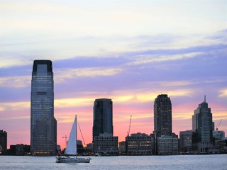 Jersey City skyline at sunset with sail boat in harbour
