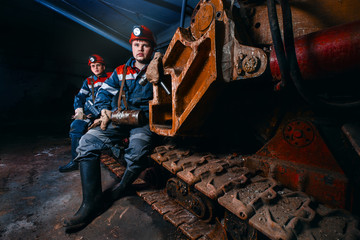 Working miners are in the mine. Men in robes and helmets. The concept of team work underground.