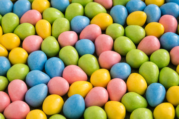 Fototapeta na wymiar Yellow, pink, blue, and green Easter candy on a green background 