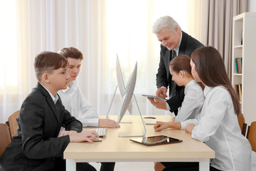 Senior teacher and pupils working with computers in classroom