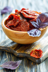 Wooden bowl with sun-dried tomatoes and purple basil.