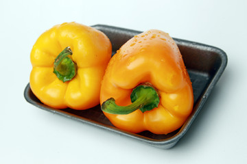 Два желтых перца в пластиковом контейнере