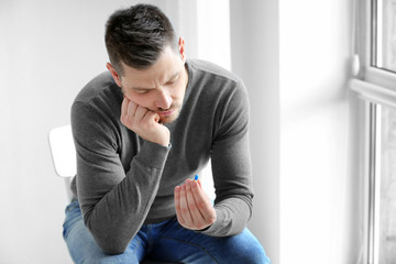 Handsome young man with pill at home