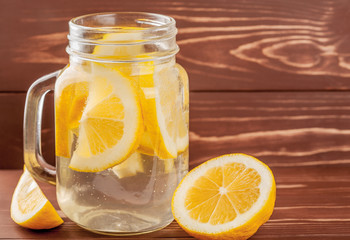 water with lemon on a wooden background