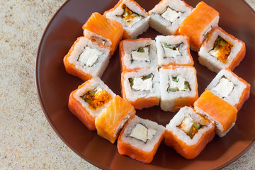Sushi set on a stone background - roll Philadelphia classic, roll Cheese salmon and roll Jamaica with pickled ginger and soy sauce.