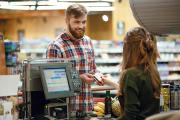 Happy young man standing in supermarket shop