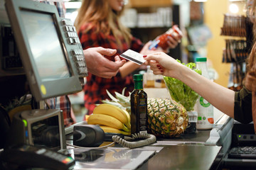 Cropped picture of young man gives credit card to cashier - obrazy, fototapety, plakaty