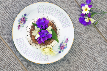 La panna cotta decorata con il cacao e con i fiorellini primaverili freschi