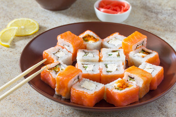 Sushi set on a stone background - roll Philadelphia classic, roll Cheese salmon and roll Jamaica with pickled ginger and soy sauce.
