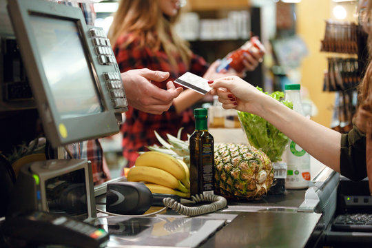 Cropped picture of young man gives credit card to cashier