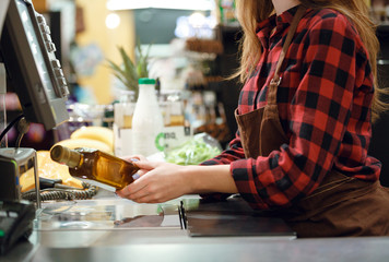 Cashier lady on workspace in supermarket shop.