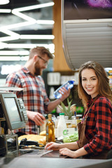 Cashier lady on workspace in supermarket shop