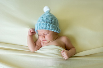 Newborn baby boy sleeping and wearing a hat