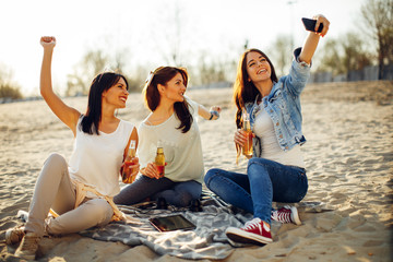 Happy young people having fun on the beach drinking beer and doing selfie