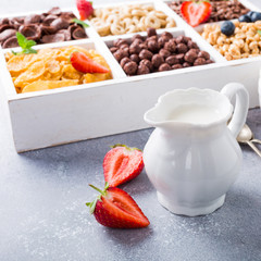 Milk jug and quick cereals with berries in white wooden box, healthy breakfast concept, selective focus, copy space.