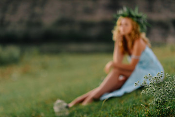 Naklejka na ściany i meble Girl on green lawn against the background of rocks