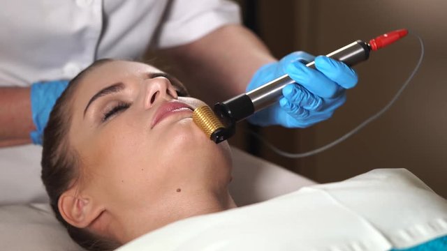 Close up roller for microneedle mesotherapy, rejuvenating treatment. Mesoporation procedure. Woman at the beautician.