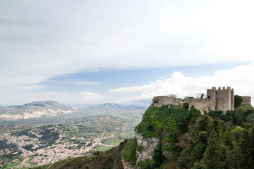 Fototapeta na wymiar A middle age castle located on Erice (Italy, Sicily, province of Trapani) with hills and a little plain town in the background