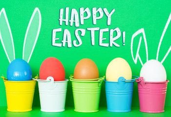 Bright dyed eggs in colored buckets with rabbit ears.  Happy Easter Card