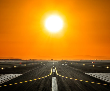 Airport runway with big sun in sunset light