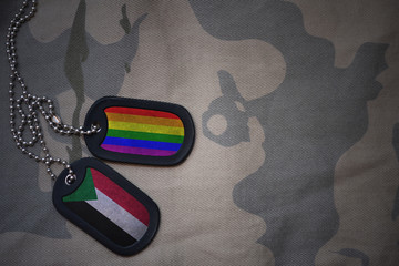 army blank, dog tag with flag of sudan and gay rainbow flag on the khaki texture background....