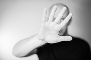 Serious young man showing stop gesture isolated on gray wall background