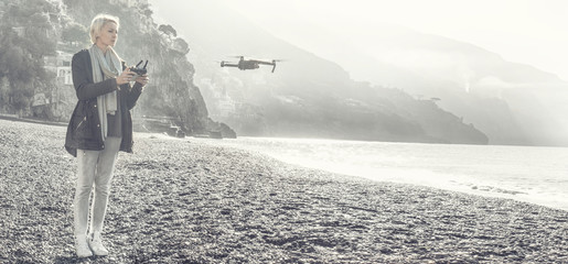 Young girl flying drone over italian coast.