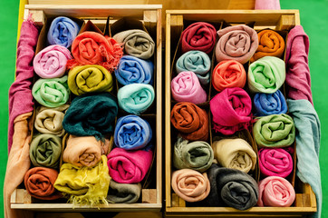many pashmina foulards rolled up in a wooden crate on a market stall