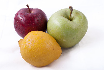 Green and red apples and yellow lemon on a white background