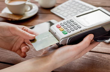 Online payment concept with credit card and terminal on wooden background