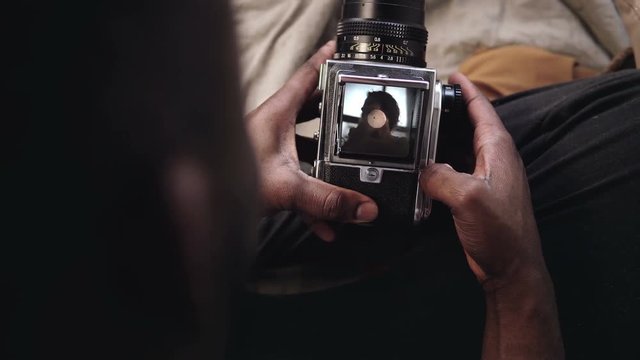 Close-up view of man opens a video recorder cover of old moving-fil camera. Photographer takes the photo of young woman.