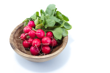 Radish with green leaves in a natural wood bowl isolated in white background - view from the top