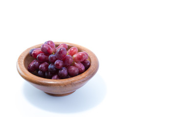 Ripe fresh red, purple grapes in a natural wood bowl isolated in white background