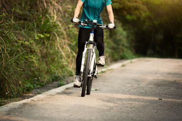 Fototapeta na wymiar Young woman riding mountain bike on forest trail