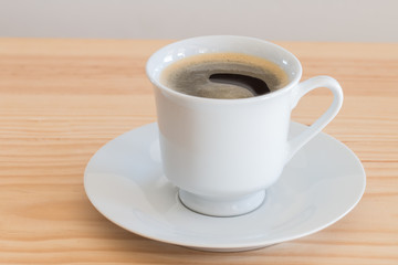 Cup of coffee on wooden table, close up.