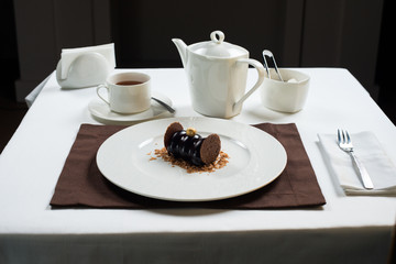 chocolate cake on a white plate . white tea set