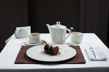 chocolate cake on a white plate . white tea set