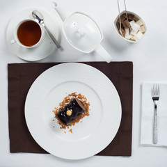 chocolate cake on a white plate . white tea set
