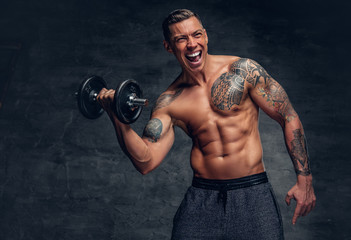 Fototapeta na wymiar Athletic male with tattoo on his chest doing biceps workouts with dumbbell.