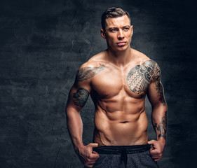 A man with tattoo on his chest over grey background.