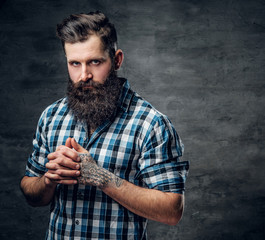 Bearded male with a tattoo on his arm dressed in a blue fleece shirt.