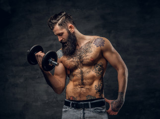 Fototapeta na wymiar Shirtless bearded male with tattooed torso doing workout with dumbbell.