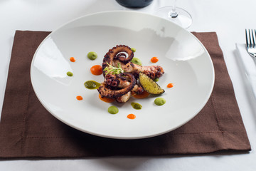 close up of cooked octopus on a white plate
