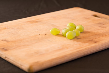 A bunch of grapes of a wooden chopping board.