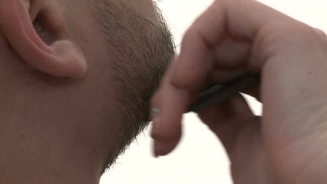 Barber shop, the Barber trims the beard of a bearded man